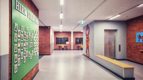 Schulflur, an dem Bilder der Mitarbeitenden an der Wand hängen