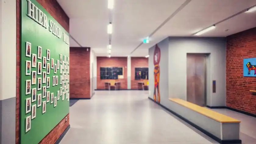 Schulflur, an dem Bilder der Mitarbeitenden an der Wand hängen